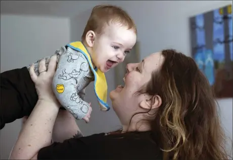  ?? ELLEN M BANNER/SEATTLE TIMES VIA AP ?? Nicole Slemp, a new mother of seven-month-old William, lifts up her son in their home, Thursday, March 14 in Auburn, Wash..