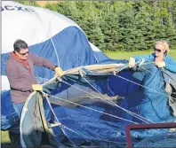  ?? RYAN ROSS/THE GUARDIAN ?? Fred Nesbitt, left, and Tara Fulop hold open a hot-air balloon as a fan inflates it before their trip near Hunter River Thursday night.