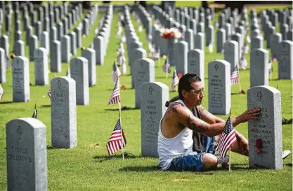  ?? Marie D. De Jesus / Houston Chronicle ?? Mario Perez on Monday visits the grave of his grandfathe­r, Julio, a World War II veteran who was laid to rest in the Houston National Cemetery, where thousands of service members are buried in the 419-acre expanse.