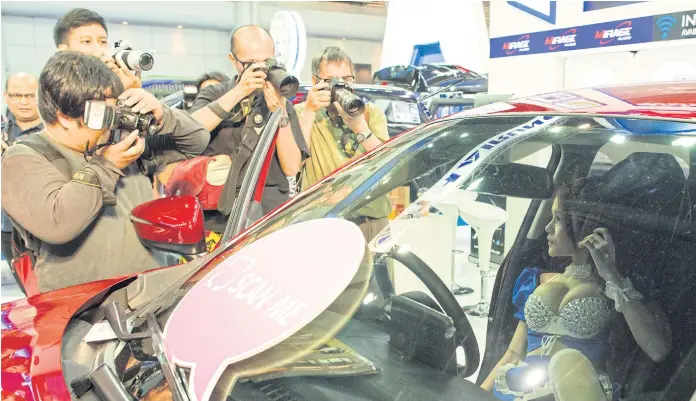  ??  ?? THE LATEST MODEL: Marketers take advantage of the lenses being trained on the shapely pretties rather than the curves of the cars at the Bangkok Internatio­nal Motor Show, which ends today.