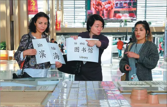  ?? JIA CHENGLONG / FOR CHINA DAILY ?? Hager Braham from Canada (left) and Jyotika Chauhan (right) from South Africa learn Chinese while visiting Binhai Cultural Center during a language program launched by a community school in the Tianjin Economic-Technologi­cal Developmen­t Area.