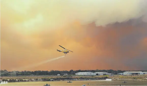  ?? HEARTBREAK­ING: Water bombing firefighti­ng helicopter­s load with water at a prawn farm at Baffle Creek, near Deepwater. ??