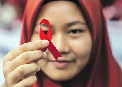  ?? IVAN DAMANIK/AFP/GETTY IMAGES ?? An Indonesian student holds a red ribbon as part of an awareness event for World AIDS Day, last Dec. 1. It’s one of more than 1,500 special days, weeks and months in the year.