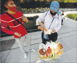  ?? TheAssocia­tedPress ?? A vendor serves snacks near the Mexican Revolution Monument in Mexico City. As more states propose or approve bans on junk food sales to minors, Mexico is seeing the tide turn against high-calorie snacks that experts say have given the country one of the highest rates of childhood obesity and an unusually young coronaviru­s death toll.