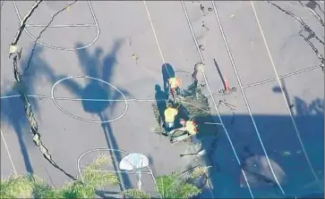  ?? KTLA ?? A CREW works to repair a basketball court at Linda Esperanza Marquez High School in Huntington Park after the ground beneath it subsided. Officials said it would take two to three months to repair the court.