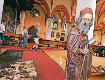  ?? RP-FOTO: JÖRG KNAPPE ?? Der Heilige Antonius, vorn im Bild, wird einen neuen Platz in einer anderen Kirche bekommen. Im Hintergrun­d tragen Bruderscha­ftler von St. Magdalena Schier und St. Pankratius Amern die Bänke aus der Kirche.