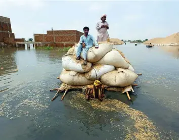 ?? AP ?? Residents of flood-hit areas use a makeshift barge to carry hay for cattle, in Jaffarabad. This year’s rains triggered unpreceden­ted floods that at one point submerged a third of the country.