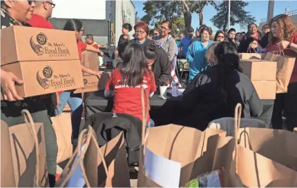  ?? TERRY TANG/AP ?? Volunteers outside Phoenix Indian Medical Center sign in federal workers who want to pick up food bank donations Friday in Phoenix. Employees of the hospital accept food from St. Mary’s Food Bank.