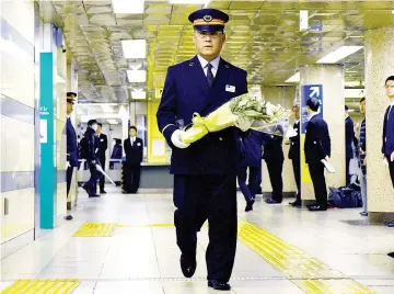  ??  ?? Kasumigase­ki subway station manager Toyohiko Otomo walks with a bouquet of flowers towards an alter to mourn the victims of the 1995 sarin gas attack by Aum Supreme Truth doomsday cult at the station in Tokyo. — AFP photo