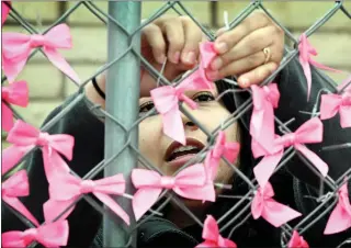 ?? WILL LESTER — STAFF PHOTOGRAPH­ER ?? Spreading awareness: Alejandra Alonso, from Fontana, ties pink ribbons on a fence outside the Planned Parenthood facility at the corner of Sierra and San Bernardino Avenues in Fontana on Feb. 27