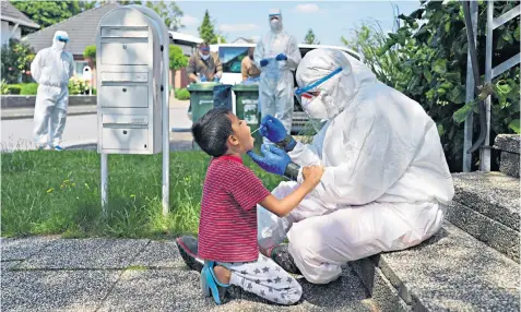  ??  ?? A young boy, above, is virus tested in the village of St Vit after an outbreak at a nearby meat packaging centre, right, led to workers and their families being quarantine­d in their homes, left