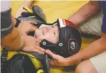  ??  ?? Paramedics secure Dr. John Dorizas’s neck as his helmet is removed while volunteeri­ng as a patient during the backboard-immobiliza­tion workshop.