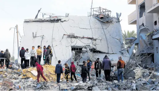  ?? AP ?? Palestinia­ns look at the destructio­n after an Israeli strike on a residentia­l building in Rafah, Gaza Strip.