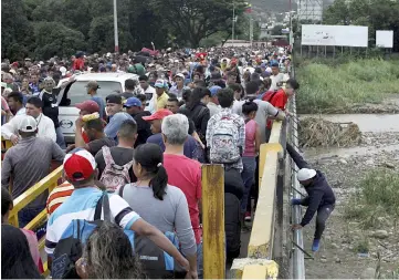  ??  ?? File photo shows a man getting off the bridge as people queue to try to cross the Venezuela-Colombia border through Simon Bolivar internatio­nal bridge in San Antonio del Tachira, Venezuela. — Reuters photo