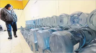  ?? CANADIAN PRESS FILE PHOTO ?? Stewart Redsky of Shoal Lake 40 First Nation walks past a week’s worth of water bottles. A new study suggests technologi­cal advances in water monitoring could reduce the number of water advisories on First Nations.