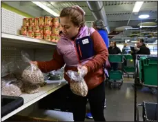  ?? ANDY CROSS — THE DENVER POST ?? Jessie Grande, a Metro Caring Food Bank program participan­t originally from Honduras, stocks up on beans for her family.