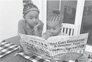  ??  ?? Second grader Skylar Tolbert, 7, peers over the shoulder of her sister, Sydney, a kindergart­ner at Libertas School of Memphis. The sisters read each night after school. Her mother says Sydney flourished when in- person classes resumed.