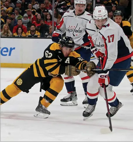  ?? STUART CAHILL — BOSTON HERALD ?? Boston Bruins left wing Brad Marchand (63) battles Washington Capitals center Dylan Strome as the Bruins take on the Capitals at the TD Garden on Saturday.