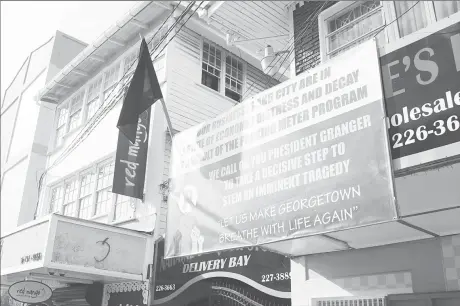  ??  ?? The front of Naraine’s Liquor Store bearing a banner with the slogan “Let us make Georgetown breathe again with life,” alongside which hangs a black flag.