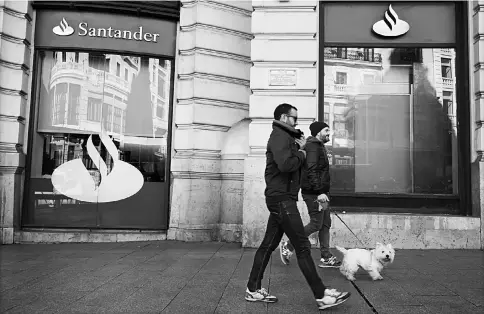  ??  ?? A pedestrian walks a dog past a Banco Santander SA bank branch in Madrid on Jan 9, 2015.