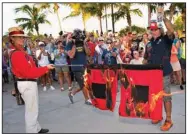  ?? (AP/Florida Keys News Bureau/Andy Newman) ?? Jai Somers (left) holds hurricane flags that were doused with rum and set on fire by Paul Menta (right) to mark the end of the 2022 Atlantic hurricane season Wednesday in Key West, Fla.