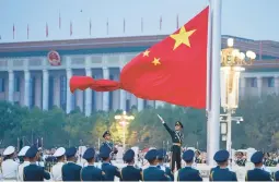  ?? CHEN ZHONGHAO/XINHUA NEWS AGENCY ?? A member of the Chinese honor guard unfurls the Chinese national flag during a ceremony held on Saturday at Tiananmen Square in Beijing.