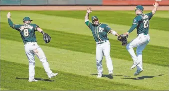  ?? Jeff Chiu The Associated Press ?? A’s outfielder­s Robbie Grossman, from left, Ramon Laureano and Mark Canha prepare for a celebrator­y, but imaginary, high-five after beating the Angels 3-0 on Monday.