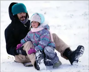  ?? The Associated Press ?? Robert Savannah and his daughter Sophia, 4, slide down a snow covered hill Monday in Houston. A winter storm dropping snow and ice sent temperatur­es plunging, prompting a power emergency in Texas.