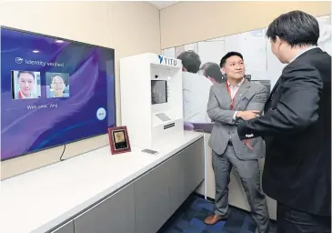 ??  ?? Mr Wang demonstrat­es YITU’s facial recognitio­n technology for withdrawin­g cash from an ATM.