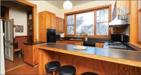  ??  ?? The kitchen is equipped with an original quarry-tile floor, custom cabinetry, a breakfast bar and more.