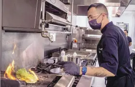  ?? ?? Chef Steven Lujan prepares charred Caesar salad at Electric Playhouse.