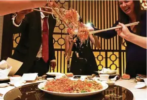  ??  ?? What is Chinese New Year without the joyous tossing of yee sang?