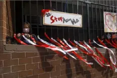  ?? Michael Loccisano/Getty Images ?? Parent coordinato­r Christina Pun puts up ribbons with messages of peace, love and hope Friday in front of Yung Wing School P.S. 124 in New York City.