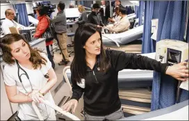  ?? ALYSSA POINTER / ATLANTA JOURNAL-CONSTITUTI­ON ?? Nurse Kristy Haynes (right) on Monday shows resident nurse Brittany Evans around a mobile medical facility outside Grady Memorial Hospital in Atlanta. The hospital added the 14-bed unit to treat flu patients. Federal officials say 1 in 14 visits to...