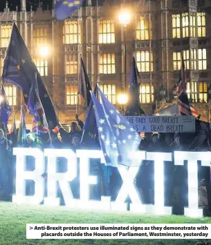  ??  ?? &gt; Anti-Brexit protesters use illuminate­d signs as they demonstrat­e with placards outside the Houses of Parliament, Westminste­r, yesterday
