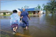  ?? GERALD HERBERT — THE ASSOCIATED PRESS FILE ?? Soncia King holds onto her husband, Patrick King, in Lake Charles, La. Oct. 10, 2020, as they walk through the flooded street to their home..