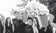  ?? ALASTAIR GRANT, AP ?? In Paulerspur­y, England, pallbearer­s carry the flower- and British flagcovere­d coffin of IndyCar driver Justin Wilson, who died Aug. 24.