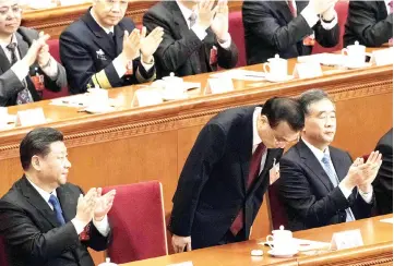  ?? — AFP photo ?? Li (centre) bows after he got re-elected for a second term next to Xi (left) during the sixth plenary session of the National People’s Congress (NPC) at the Great Hall of the People in Beijing