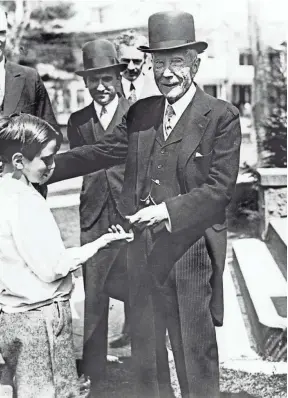  ?? AP ?? John D. Rockefelle­r gives a dime to a child in this undated picture. Warner Center in New York City.