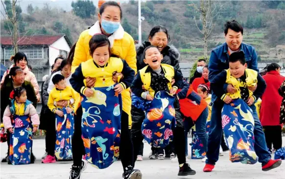  ?? ?? December 7, 2021: Parents carry their children in “pockets” and rush to the finish line in a game held at the Central Kindergart­en of Hongshi Town in Chongqing Municipali­ty. Since the release of the third-child policy, government­s at all levels have introduced incentives such as holidays and tax deduction to promote the implementa­tion of the policy. IC