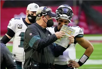  ?? RICK SCUTERI — THE ASSOCIATED PRESS ?? Philadelph­ia Eagles head coach Doug Pederson talks with starting quarterbac­k Jalen Hurts as quarterbac­k Carson Wentz (11) looks on during the first half of an NFL football game Dec. 20 in Glendale, Ariz.