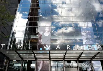  ?? AP/MARK LENNIHAN ?? Clouds are reflected Monday in the glass facade of the Time Warner building in New York. AT&T plans to buy the company in a deal valued at $108.7 billion.