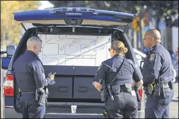 ?? JIM WILSON / THE NEW YORK TIMES ?? Police officers review a map of the scene of a fire at a warehouse in Oakland, Calif. Firefighte­rs picking through the ruins have found more bodies, raising the death toll to more than 30 from a fire that ripped through a makeshift nightclub on Friday.