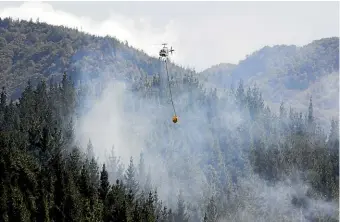  ?? RICKY WILSON/STUFF ?? A helicopter drops water on a fire in a pine plantation near Picton.