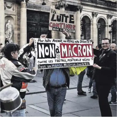  ?? Philippe Lopez / AFP ?? Manifestan­tes sostienen un cartel contra Macron durante una protesta contra la reforma de las pensiones.