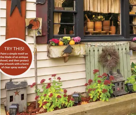  ??  ?? Flower beds can be home to more than just blooms. Each fall, Jodi “plants” a decorative shovel alongside her small handcrafte­d cabins and picket fence gate, which remain in the bed year-round.