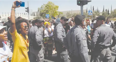  ?? (Ronen Zvulun/Reuters) ?? POLICEMEN GUARD as protesters demonstrat­e in Jerusalem. Blue and White, the only party with Ethiopian-Israeli MKs, has launched a new campaign to capture the community’s vote.