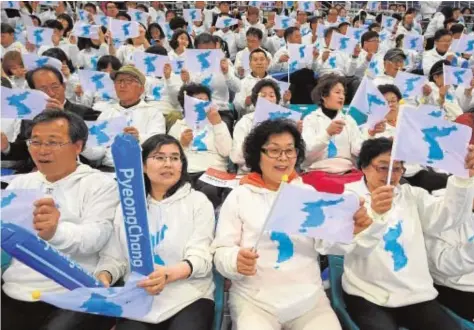  ?? AFP ?? Surcoreano­s con la bandera de una Corea unida animan a atletas del Norte en una competició­n, en Gangneung