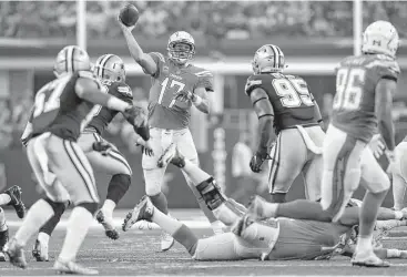  ?? Tom Pennington / Getty Images ?? Chargers quarterbac­k Philip Rivers throws over the middle of the Cowboys’ defense in the first half of Thursday’s game. Rivers threw for 434 yards and three touchdowns in his first Thanksgivi­ng Day game.