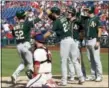  ?? TOM MIHALEK — THE ASSOCIATED PRESS ?? Oakland Athletics’ Joey Wendle is greeted at the plate by Matt Joyce and other teammates after hitting a grand slam off Phillies pitcher Edubray Ramos as Phillies catcher Cameron Rupp looks on during Sunday’s game in Philadelph­ia.